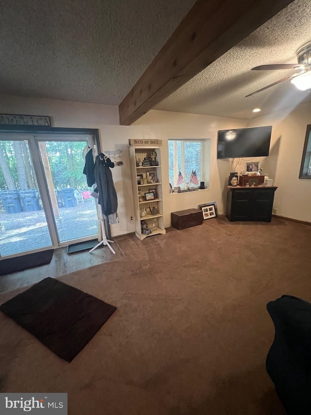 interior space with ceiling fan, a textured ceiling, and beamed ceiling