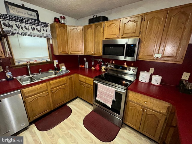 kitchen featuring appliances with stainless steel finishes, sink, and light wood-type flooring