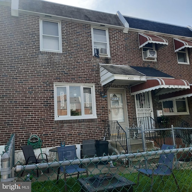 view of property featuring brick siding, a fenced front yard, and cooling unit