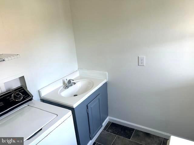 clothes washing area with dark tile patterned floors, washer / clothes dryer, and sink