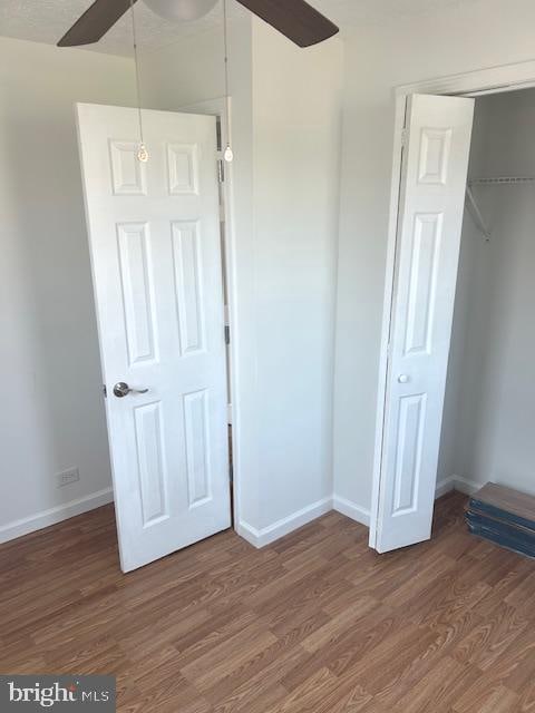 unfurnished bedroom with wood-type flooring, a closet, and ceiling fan