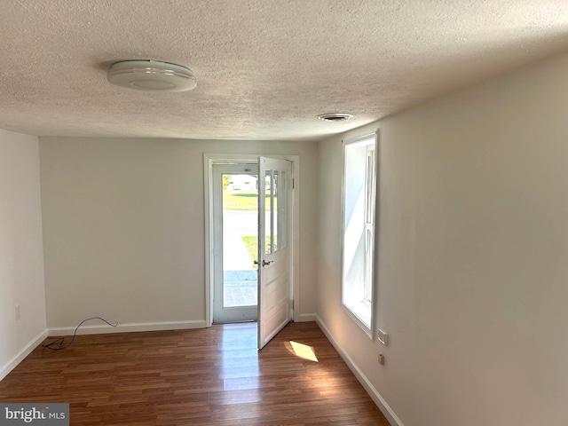 interior space featuring a textured ceiling, dark wood-type flooring, and plenty of natural light