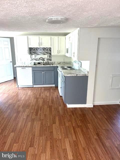 kitchen with gray cabinets, dark hardwood / wood-style floors, sink, white cabinets, and white appliances