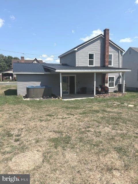 back of house featuring cooling unit, a patio area, and a yard