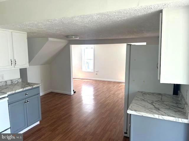 interior space featuring blue cabinets, white cabinets, a textured ceiling, and dark hardwood / wood-style floors