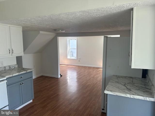 interior space featuring white range oven, dark wood-type flooring, white cabinets, blue cabinetry, and a textured ceiling