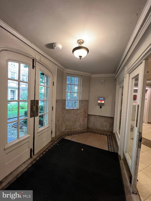 doorway to outside with a wainscoted wall, crown molding, and french doors