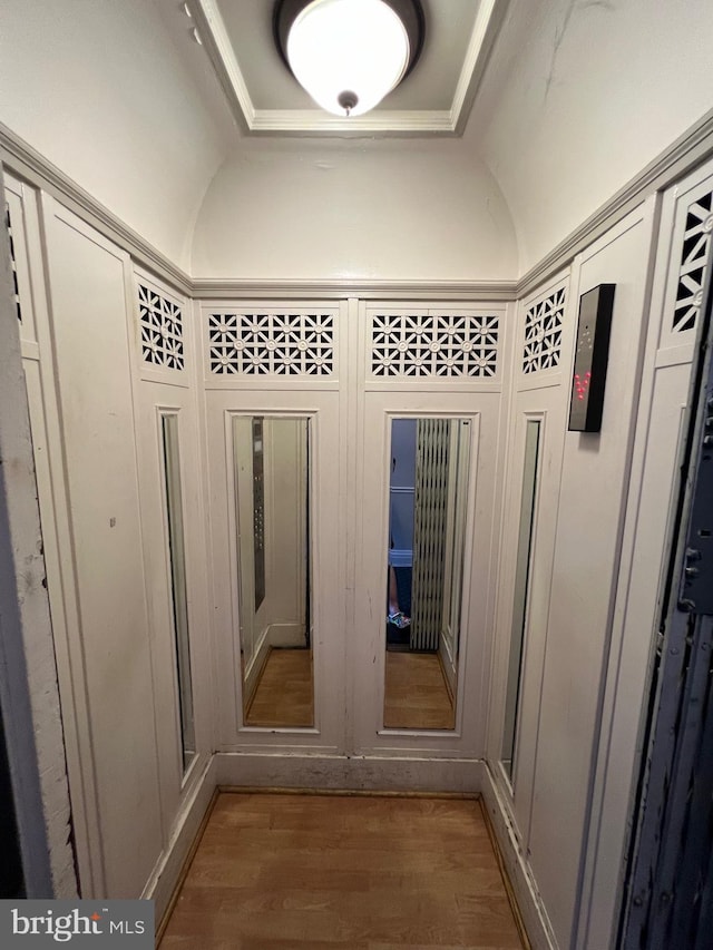 mudroom with a tray ceiling and wood finished floors