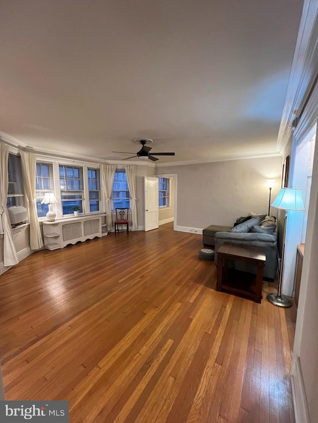 interior space with baseboards, ceiling fan, ornamental molding, and hardwood / wood-style flooring