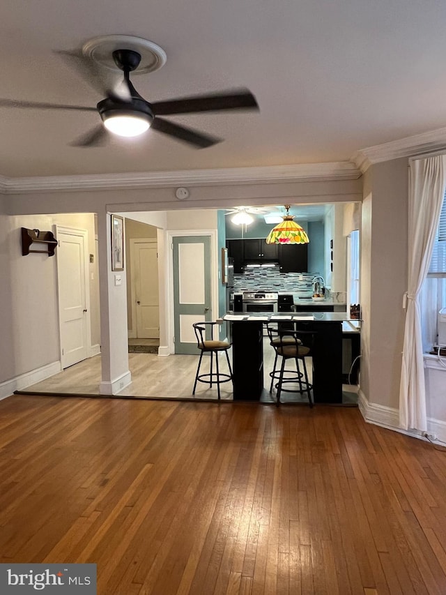 kitchen with light wood finished floors, decorative backsplash, a breakfast bar, and ornamental molding