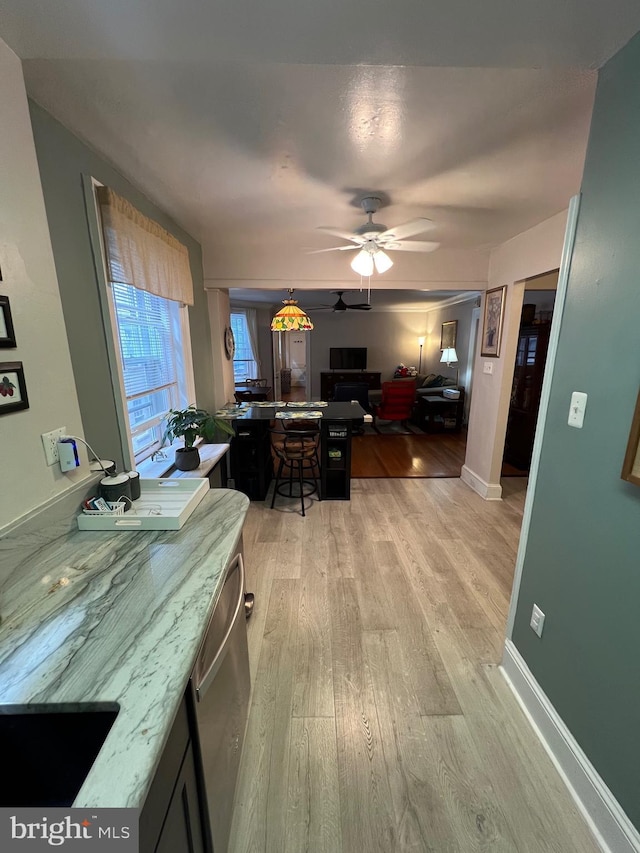 interior space with baseboards, light wood-style flooring, dishwasher, a kitchen breakfast bar, and open floor plan