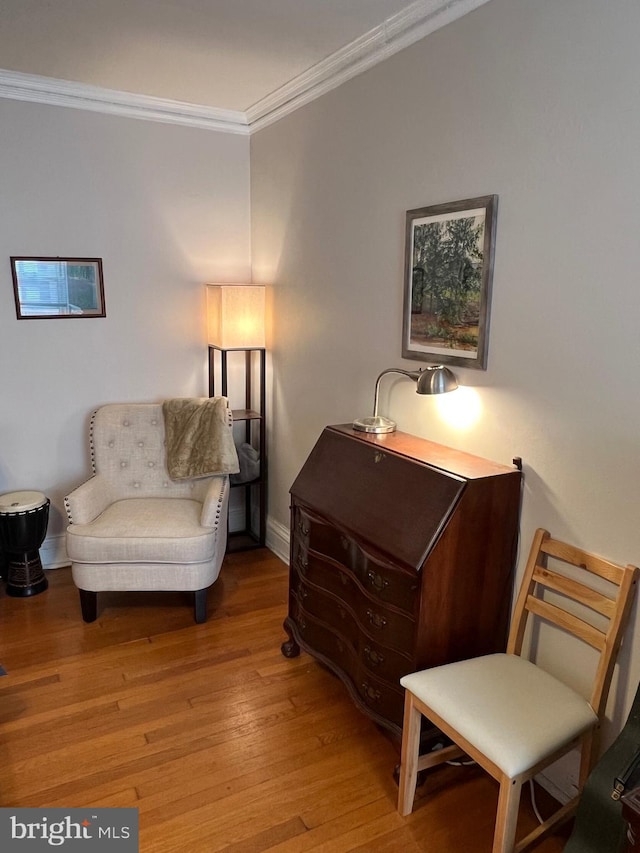 sitting room featuring baseboards, wood finished floors, and crown molding