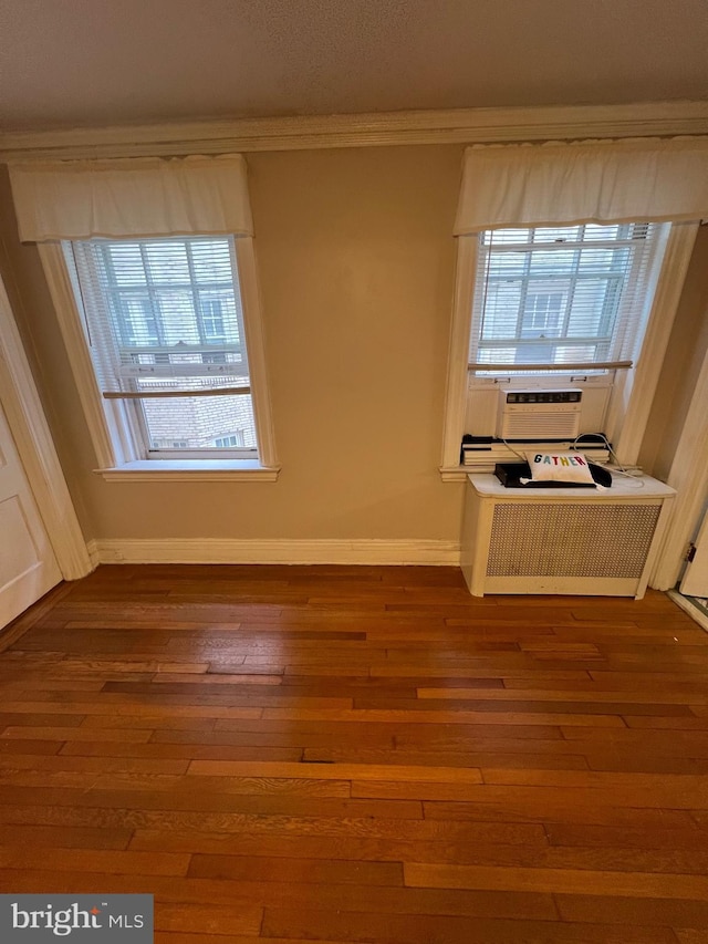 unfurnished room with dark wood finished floors, cooling unit, crown molding, and baseboards