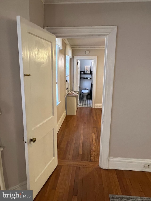 corridor with hardwood / wood-style floors, crown molding, and baseboards