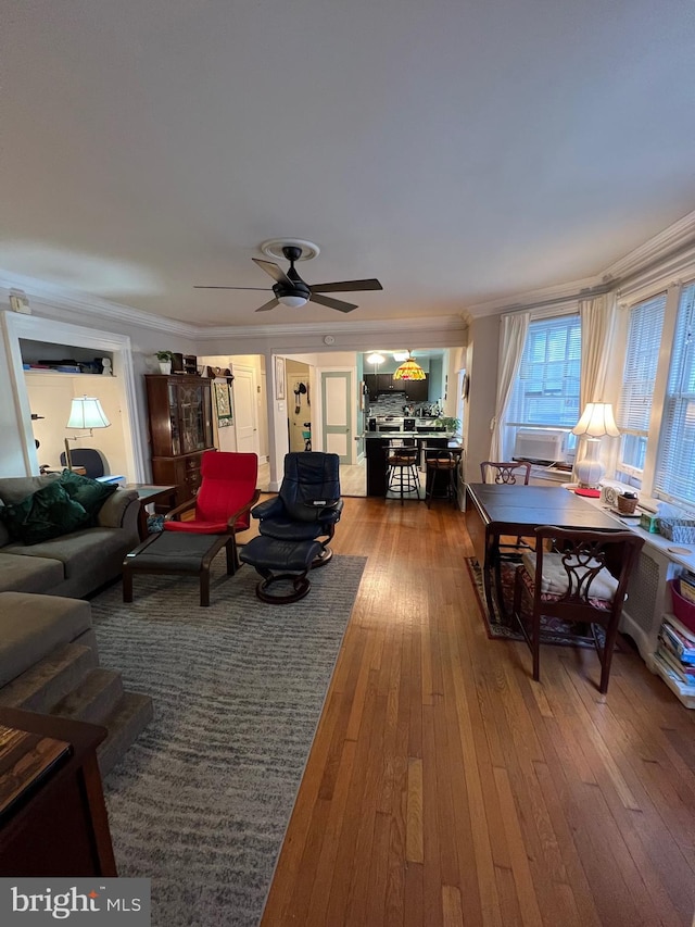 living room with hardwood / wood-style flooring, crown molding, and ceiling fan