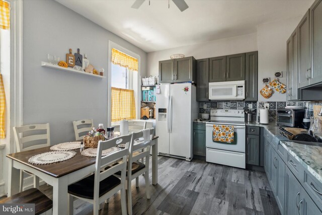 kitchen with white appliances, gray cabinets, ceiling fan, tasteful backsplash, and hardwood / wood-style flooring