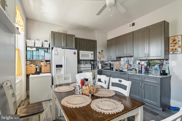 kitchen with decorative backsplash, ceiling fan, gray cabinets, white appliances, and wood-type flooring