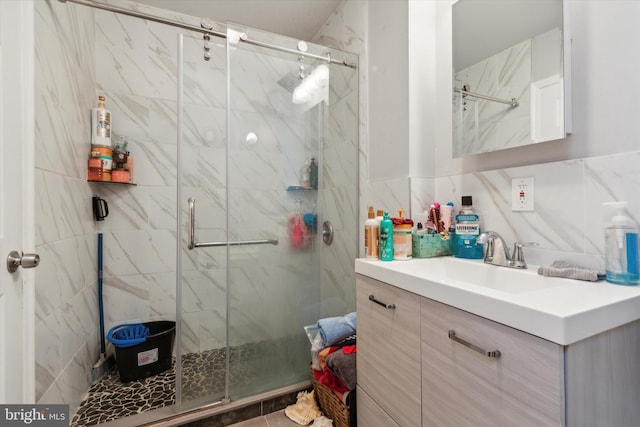 bathroom featuring tile patterned floors, tile walls, a shower with door, and vanity