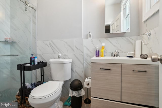 bathroom featuring vanity, toilet, a shower with door, and tile walls