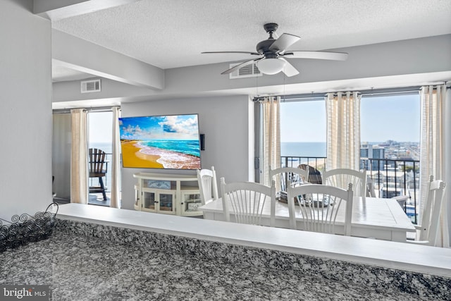 dining room with a textured ceiling, ceiling fan, and visible vents