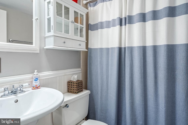 bathroom featuring wainscoting, a sink, and toilet