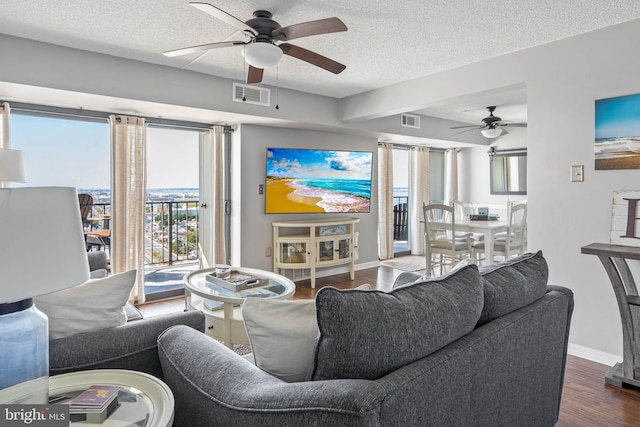 living room with baseboards, visible vents, dark wood finished floors, and a textured ceiling