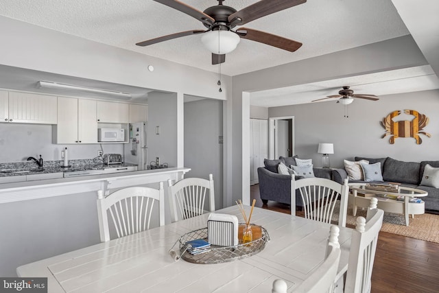 dining area with dark wood-style floors, a textured ceiling, a ceiling fan, and a toaster