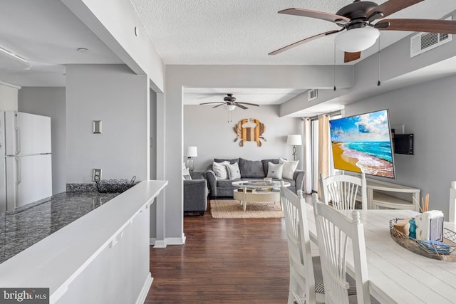 dining area with dark wood-style floors, a textured ceiling, visible vents, and a ceiling fan