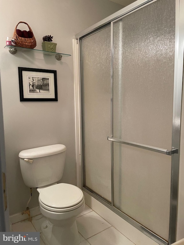 bathroom featuring toilet, walk in shower, and tile patterned flooring