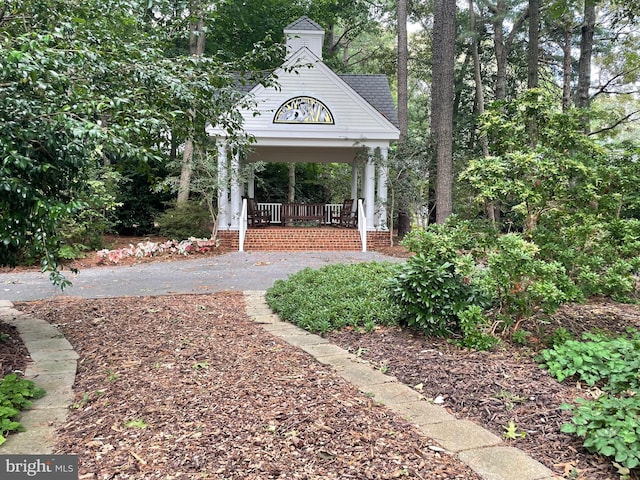 view of yard featuring aphalt driveway and a porch