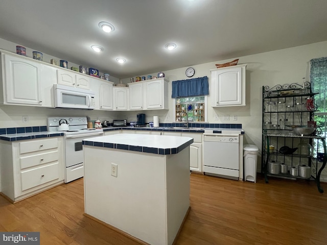 kitchen featuring light wood-type flooring, white appliances, white cabinetry, tile counters, and a kitchen island