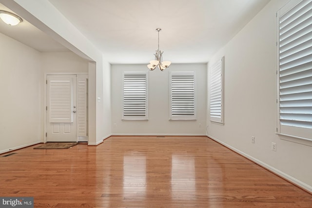 spare room with a chandelier and light hardwood / wood-style floors