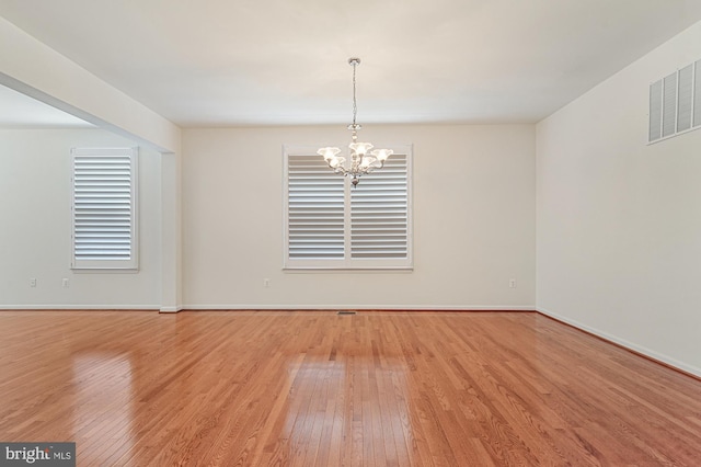 unfurnished room with light wood-type flooring and a chandelier