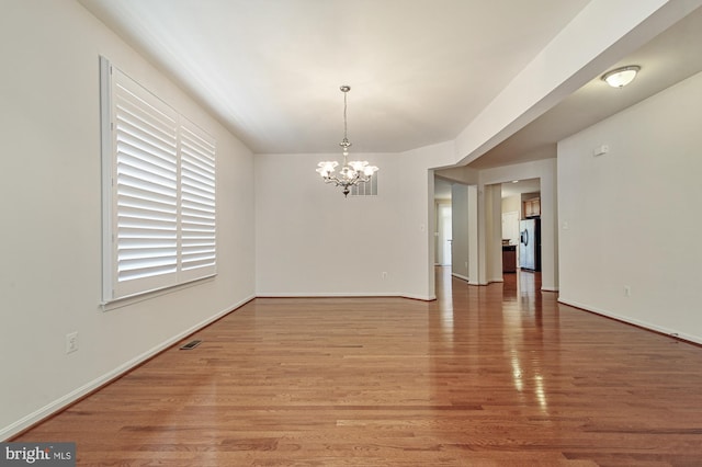 empty room featuring hardwood / wood-style floors and an inviting chandelier