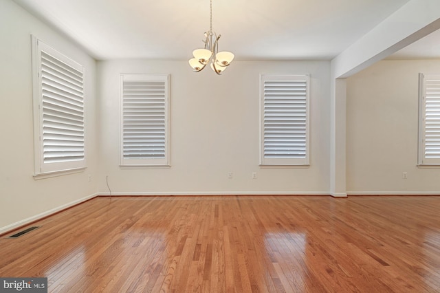 spare room featuring an inviting chandelier and light hardwood / wood-style floors