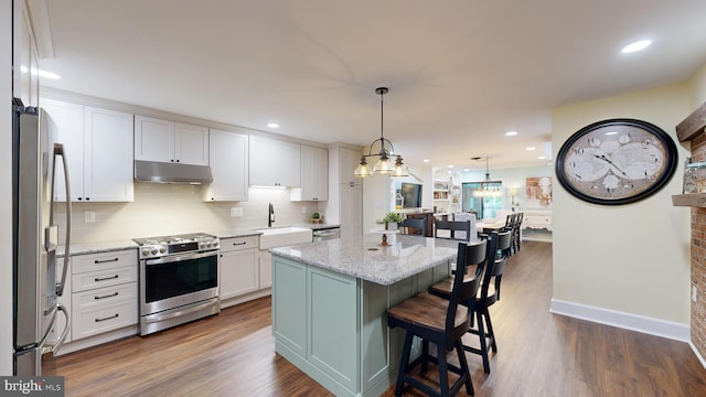 kitchen featuring appliances with stainless steel finishes, dark wood-type flooring, white cabinets, and light stone countertops