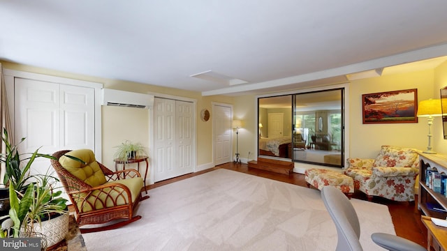 sitting room with a wall mounted air conditioner and hardwood / wood-style flooring