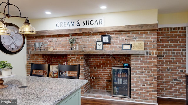 kitchen featuring brick wall, light stone counters, and dark hardwood / wood-style floors