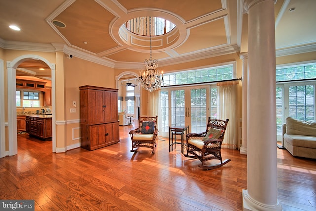 living area with arched walkways, coffered ceiling, wood finished floors, and ornate columns