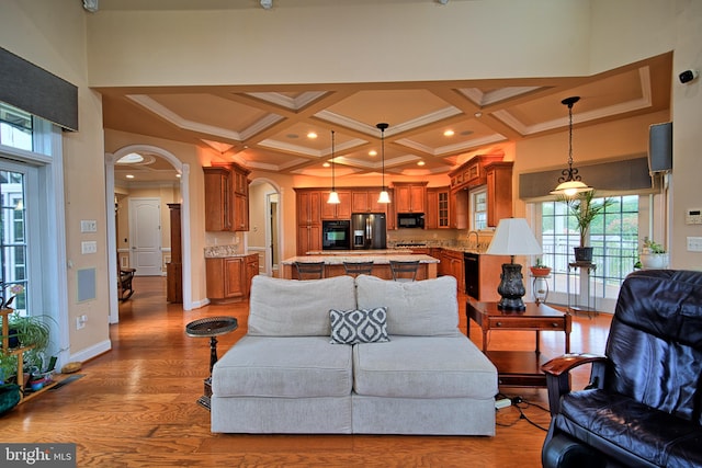 living room featuring arched walkways, recessed lighting, coffered ceiling, wood finished floors, and baseboards