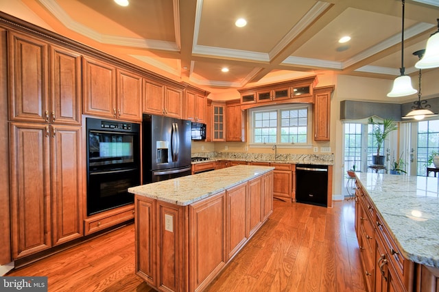 kitchen featuring black appliances, light stone countertops, glass insert cabinets, and a center island