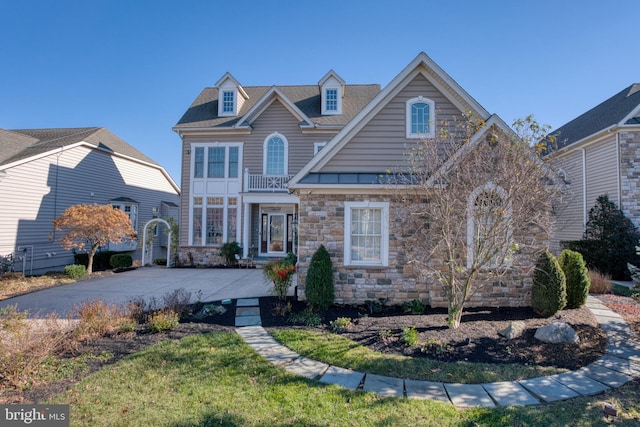 view of front of home with stone siding, a front lawn, and driveway