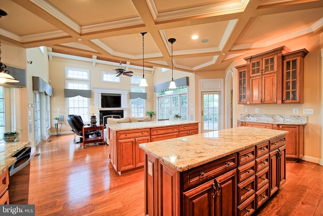 kitchen featuring a center island, decorative light fixtures, a fireplace, glass insert cabinets, and open floor plan