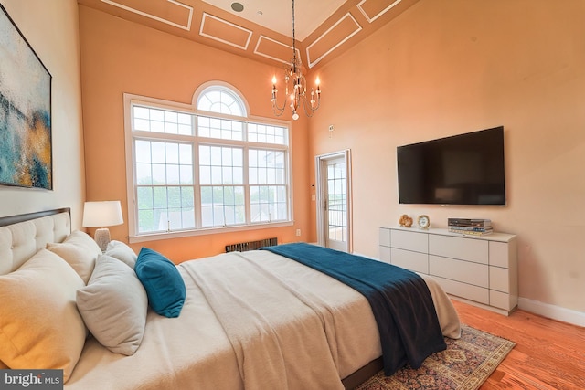 bedroom with light wood-style floors, radiator, baseboards, and an inviting chandelier