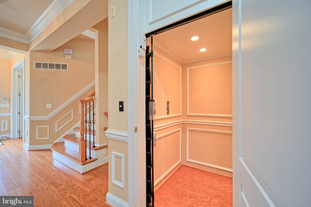 interior details with elevator, visible vents, a decorative wall, and wood finished floors