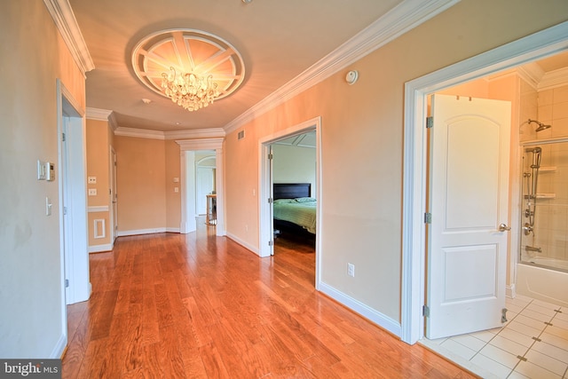 corridor featuring baseboards, ornamental molding, light wood-style flooring, and an inviting chandelier