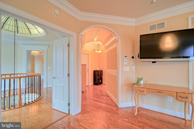 corridor with arched walkways, crown molding, visible vents, wood finished floors, and a chandelier