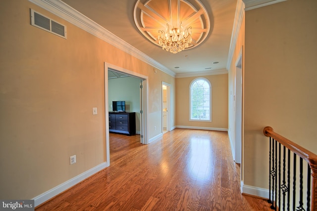 interior space with a notable chandelier, wood finished floors, visible vents, baseboards, and ornamental molding