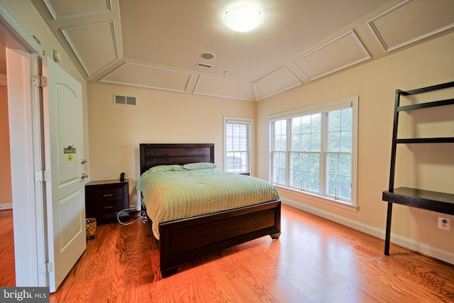 bedroom featuring baseboards, attic access, visible vents, and wood finished floors