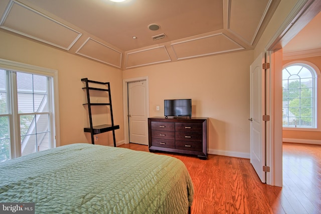 bedroom featuring light wood-style floors, visible vents, crown molding, and baseboards